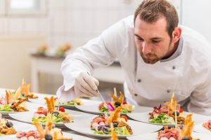 Male chef garnishing his appetizer plate, ready to serve